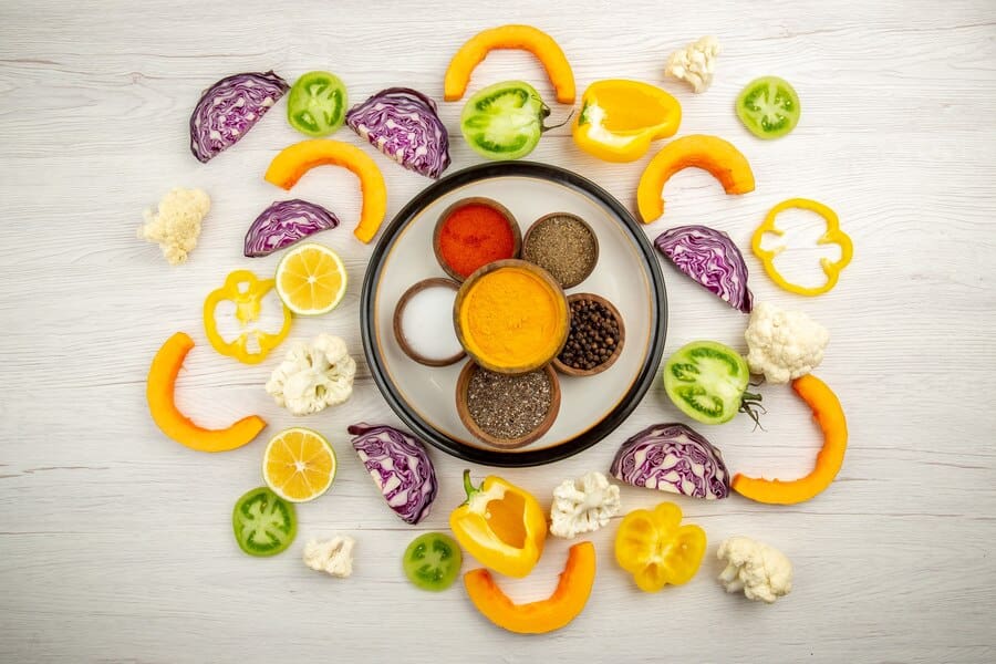 bowls with spices on round plate turmeric salt black pepper red pepper chopped vegetables